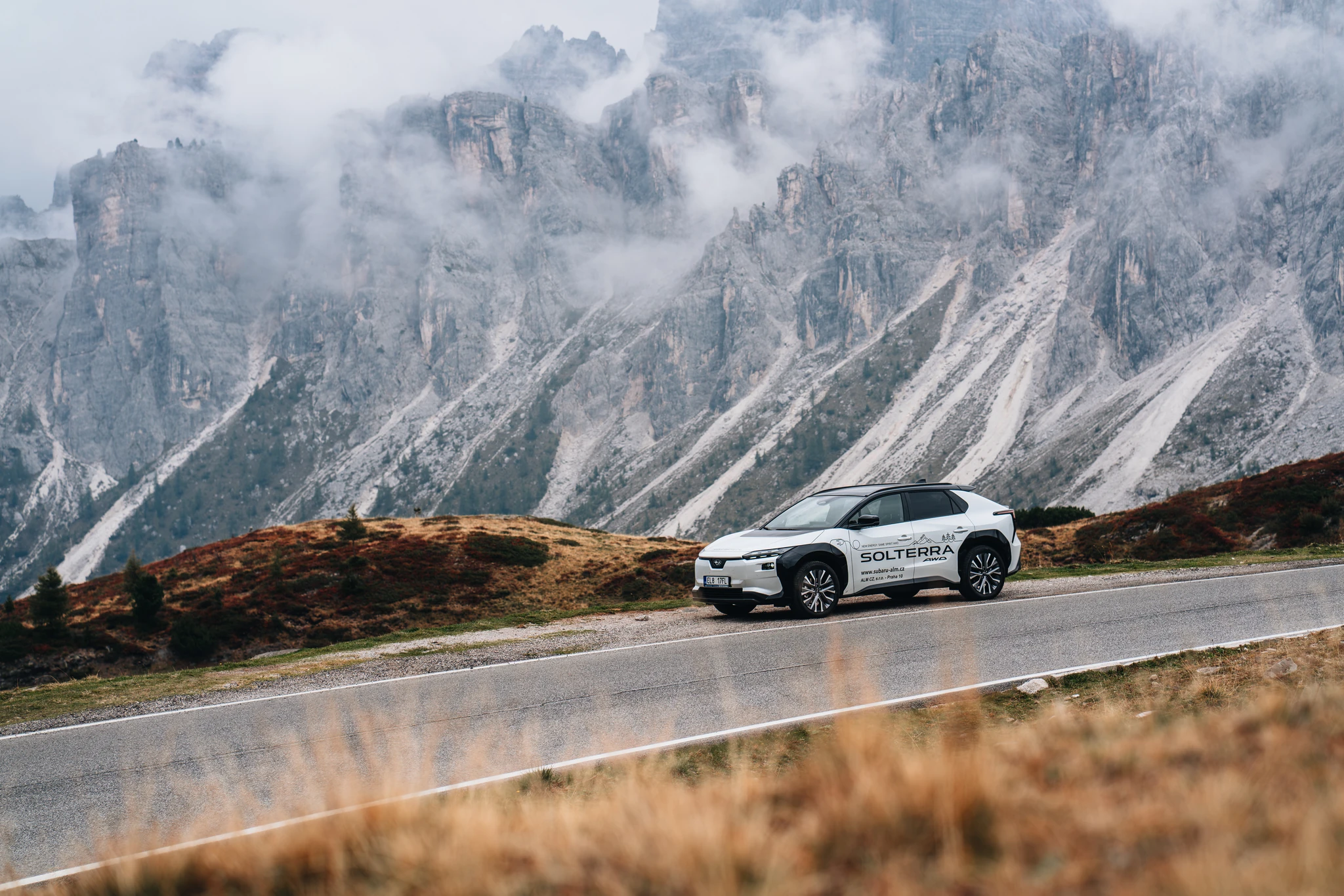 Bílá Subaru Solterra pod skalní stěnou v Dolomitech